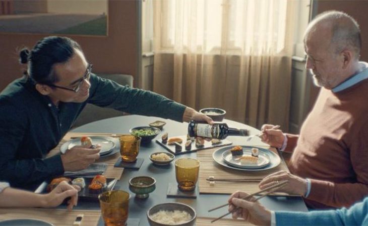 uomo asiatico versa aceto ponti su piatto di uomo europeo a tavola